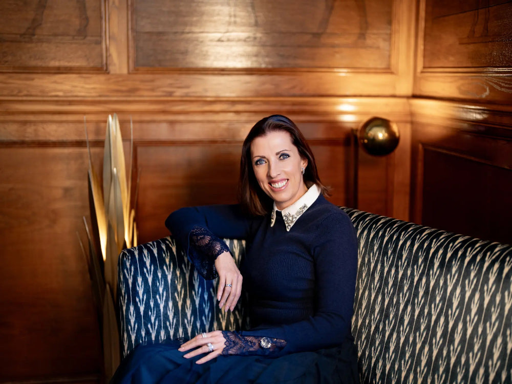 Woman sitting on a patterned sofa in a room with wooden paneling.