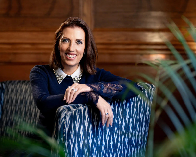 Woman sitting on a blue and white patterned chair with a wooden background
