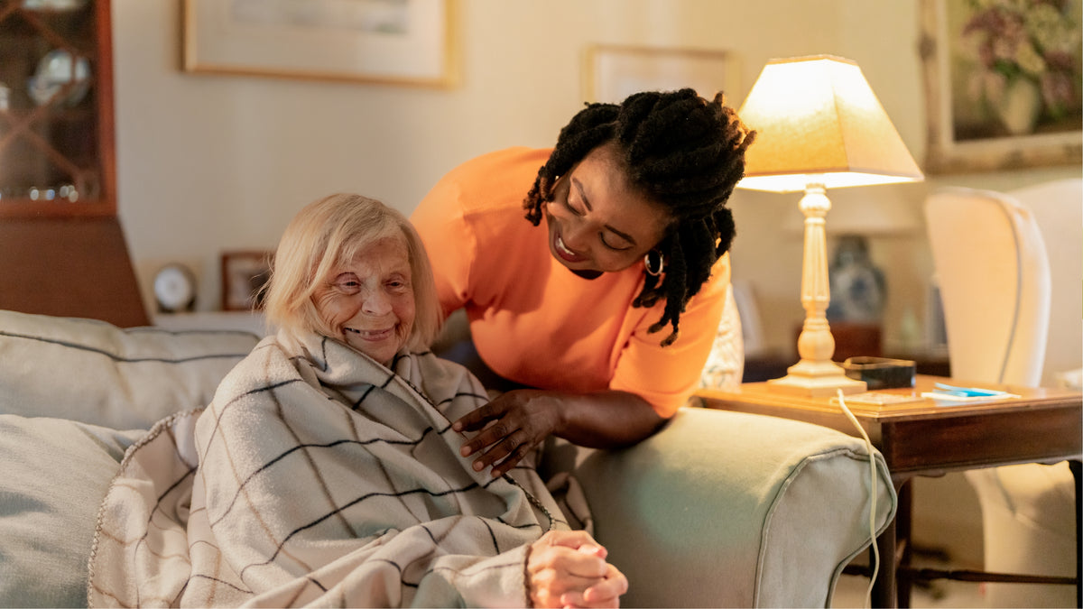Live-in carer sharing a warm moment with an older woman at home.