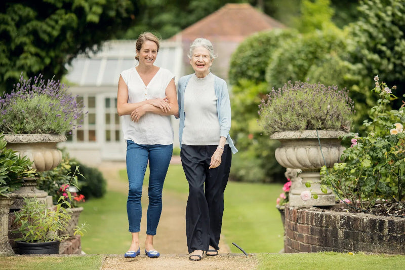 Two women walking together in a garden setting