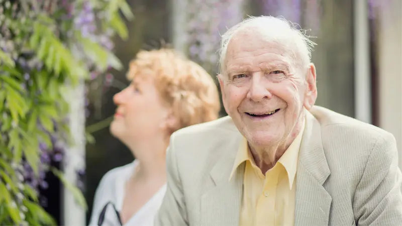 Man in a light suit smiling outdoors with blurred background