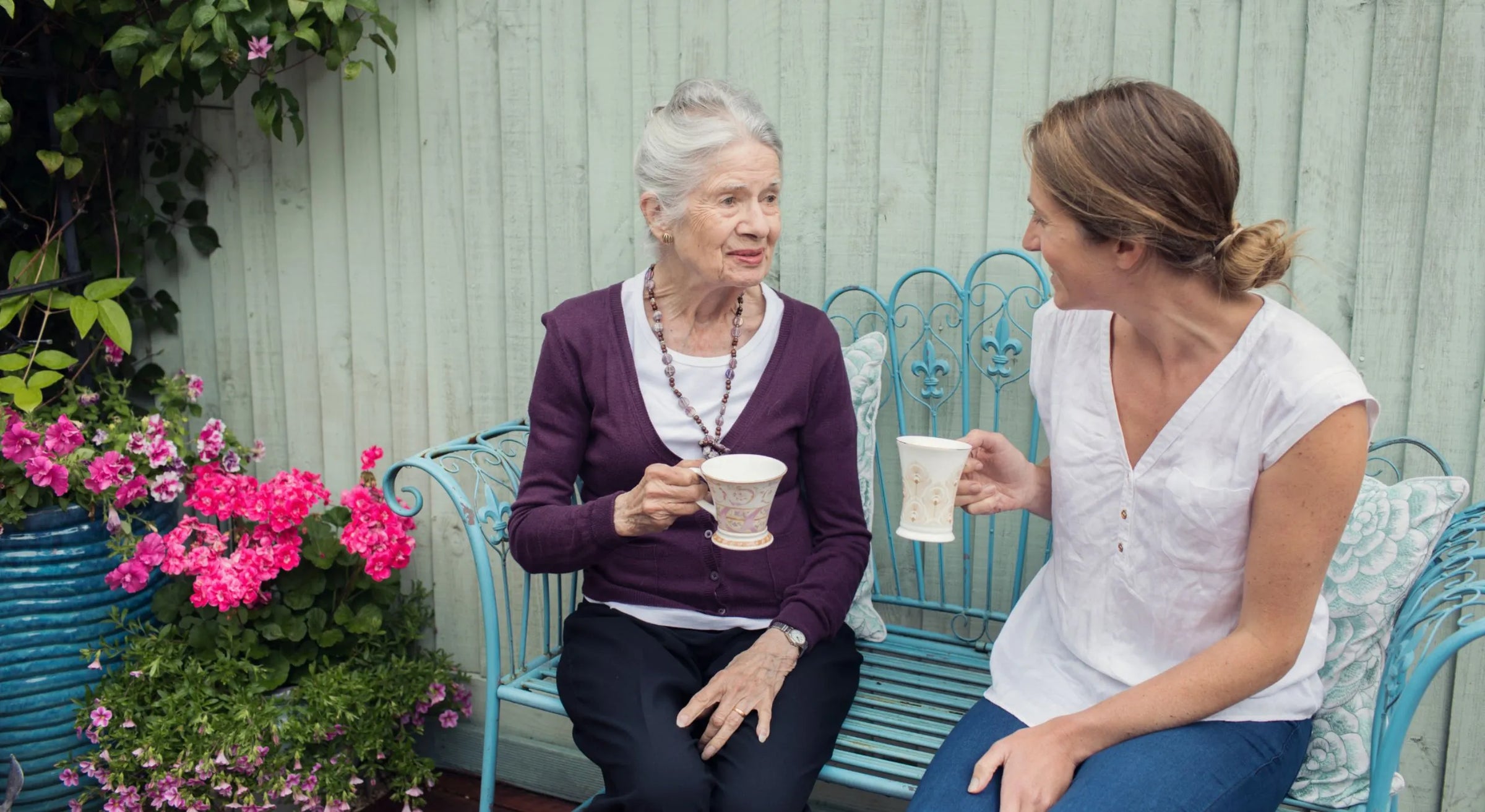 Live-in carer sharing a conversation with an elderly lady at home.