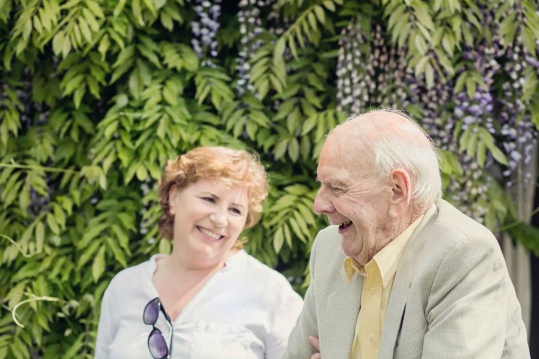 Elderly live-in care client and carer smiling in garden